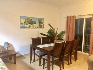 Uma área de refeições com uma mesa, cadeiras, uma planta e um quadro na parede.