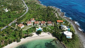 Vista aerea di una località balneare con diverse ville, una spiaggia e una piscina.