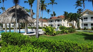 Um resort com piscina, palmeiras e uma construção de palha.