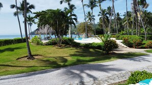 Un resort con piscina, palme e vista sull'oceano.
