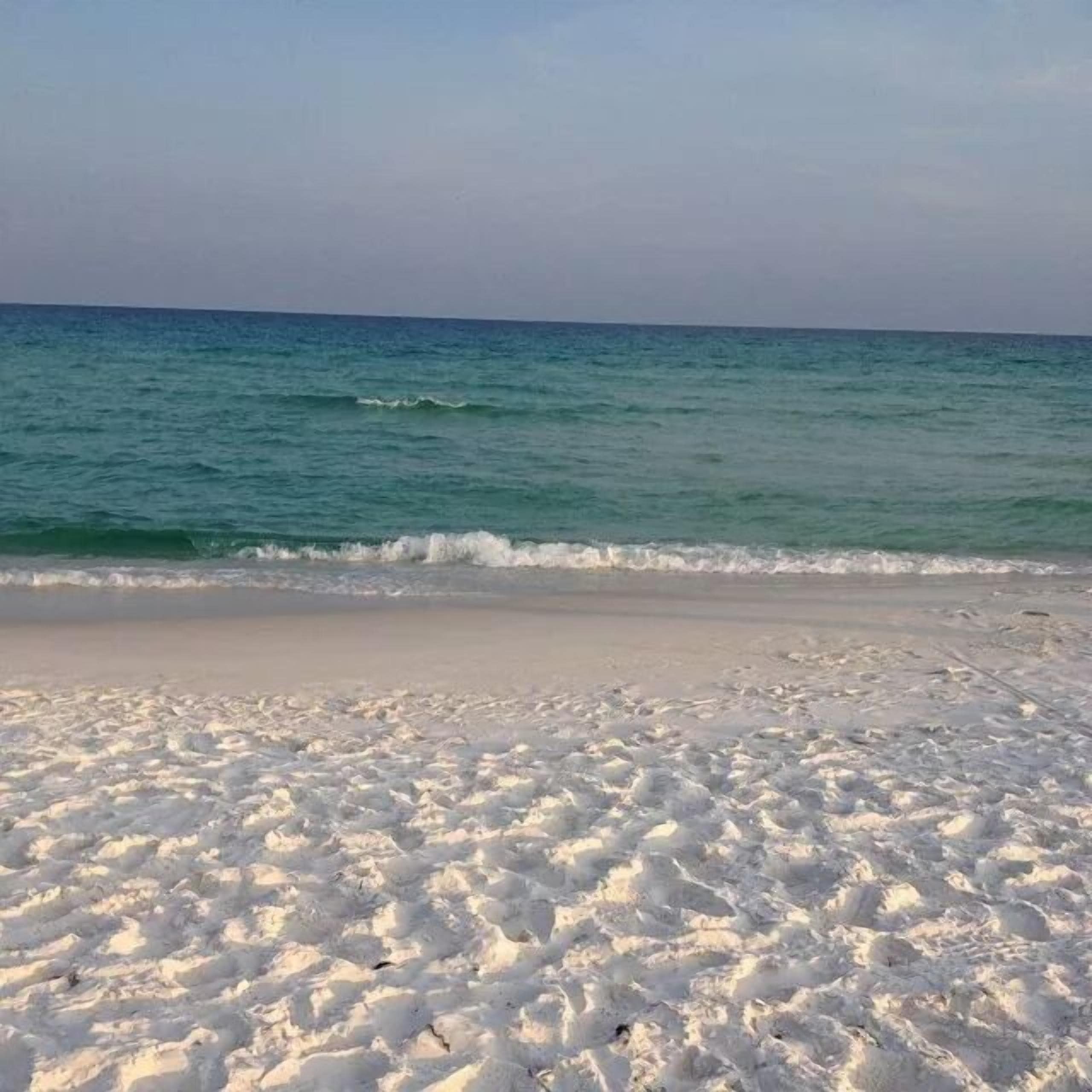 Una spiaggia con sabbia bianca e onde calme.