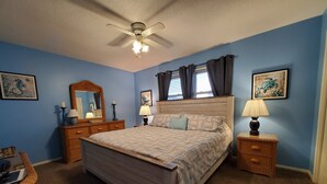 A bedroom with a bed, nightstands, a dresser, a ceiling fan, and artwork on the walls. - White Sandy Beaches, Gulf Front Complex, Heated Pool, Private Patio (Navarre)