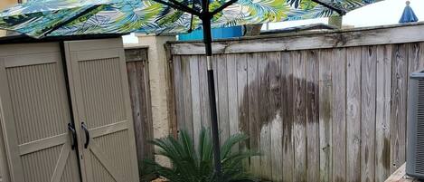 A patio with a table and chairs, a wooden fence, and a palm tree.