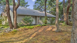 A single-story house with a sloped roof, surrounded by trees and a stone pathway leading to the front door. - Rare Strait of Juan de Fuca no-bank water front, near mouth of Elwha River. (port angeles)
