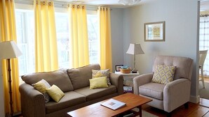 A living room with a sofa, armchair, coffee table, and a ceiling fan.
