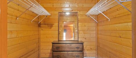 A narrow hallway with wooden walls, a central wooden dresser with drawers, and metal shelving units on either side.