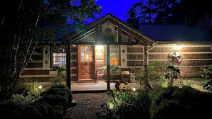 Eine rustikale Holzhütte mit einer Holztür, einer Veranda mit einer Bank und einer Steinmauer mit einem Sternwappen.