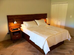 A neatly made bed with white linens, wooden headboard, bedside tables with lamps, and a closed white closet. - Amazing Waterfront Escape: Balcony, Renovated, Paradise At A Great Price! (Saint Thomas)