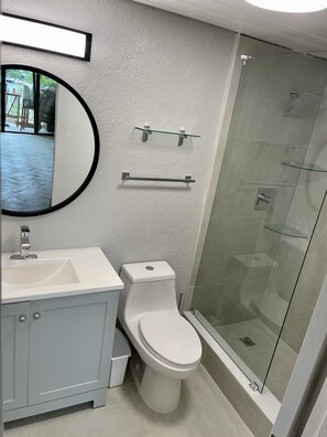 A modern bathroom with a white sink, toilet, and glass shower enclosure. - Amazing Waterfront Escape: Balcony, Renovated, Paradise At A Great Price! (Saint Thomas)
