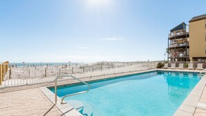 Una piscina con vista a la playa y un edificio con balcones.