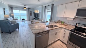 Una cocina moderna con una isla grande, electrodomésticos de acero inoxidable y vistas al océano.