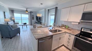 A modern kitchen with a large island, stainless steel appliances, and a view of the ocean.