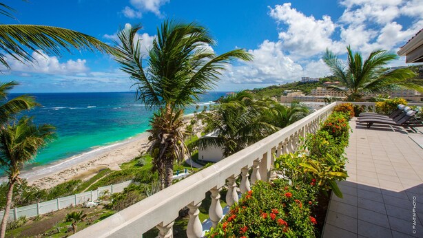 A coastal view with a beach, palm trees, and a balcony with outdoor seating. - FantaSea beachfront, every bedroom facing ocean! Remodeled 2024 (Upper Prince's Quarter)