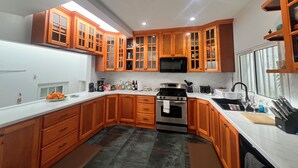A kitchen with wooden cabinets, a stainless steel stove, a microwave, and a sink. - FantaSea beachfront, every bedroom facing ocean! Remodeled 2024 (Upper Prince's Quarter)