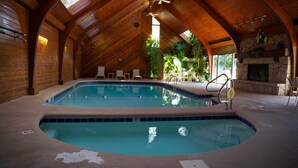 An indoor swimming pool with a wooden ceiling and stone fireplace. - Spacious Condo with in condo private Hot Tub (Osage Beach)