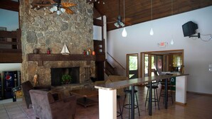 A spacious living area with a stone fireplace, comfortable seating, and a bar area with stools. - Spacious Condo with in condo private Hot Tub (Osage Beach)
