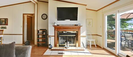 Una sala de estar con chimenea, un televisor montado encima y una puerta que da a otra habitación.