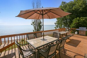 Una terraza de madera con una mesa, sillas, un paraguas y una parrilla.
