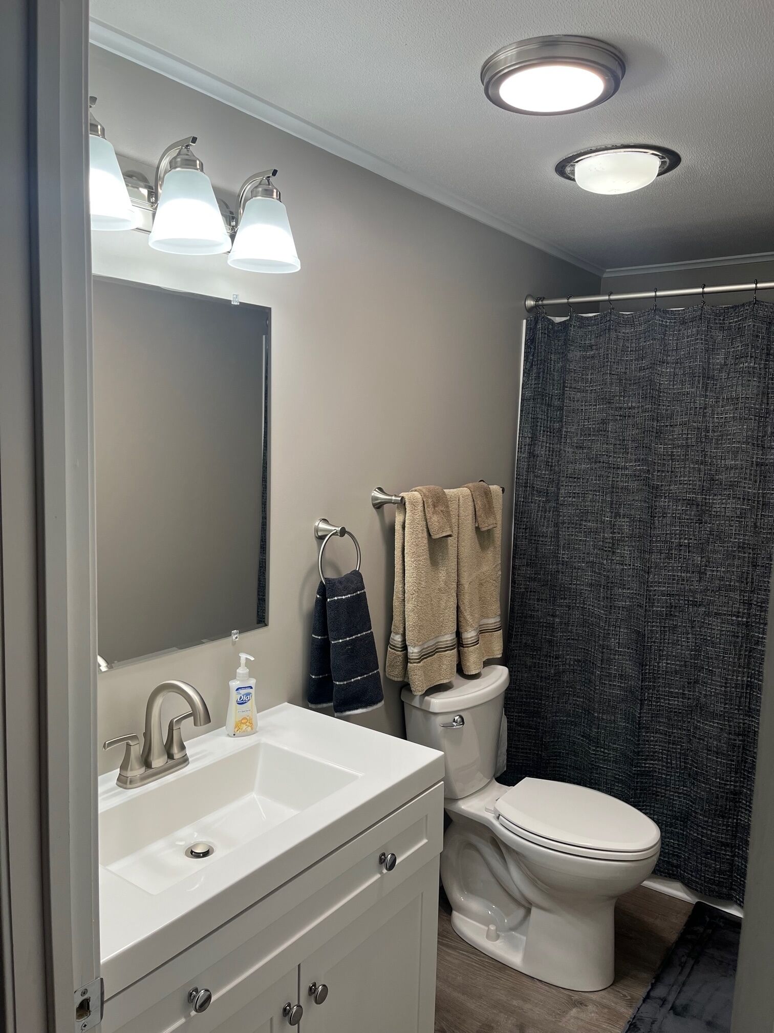 A bathroom with a white sink, a mirror, a toilet, and a shower curtain.