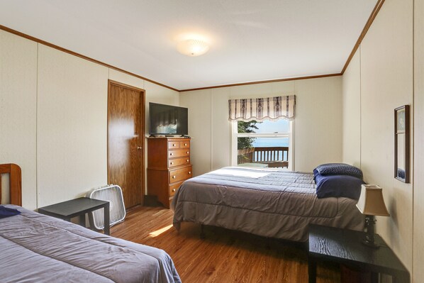 Un dormitorio con dos camas, un tocador, un televisor y una ventana con vistas.