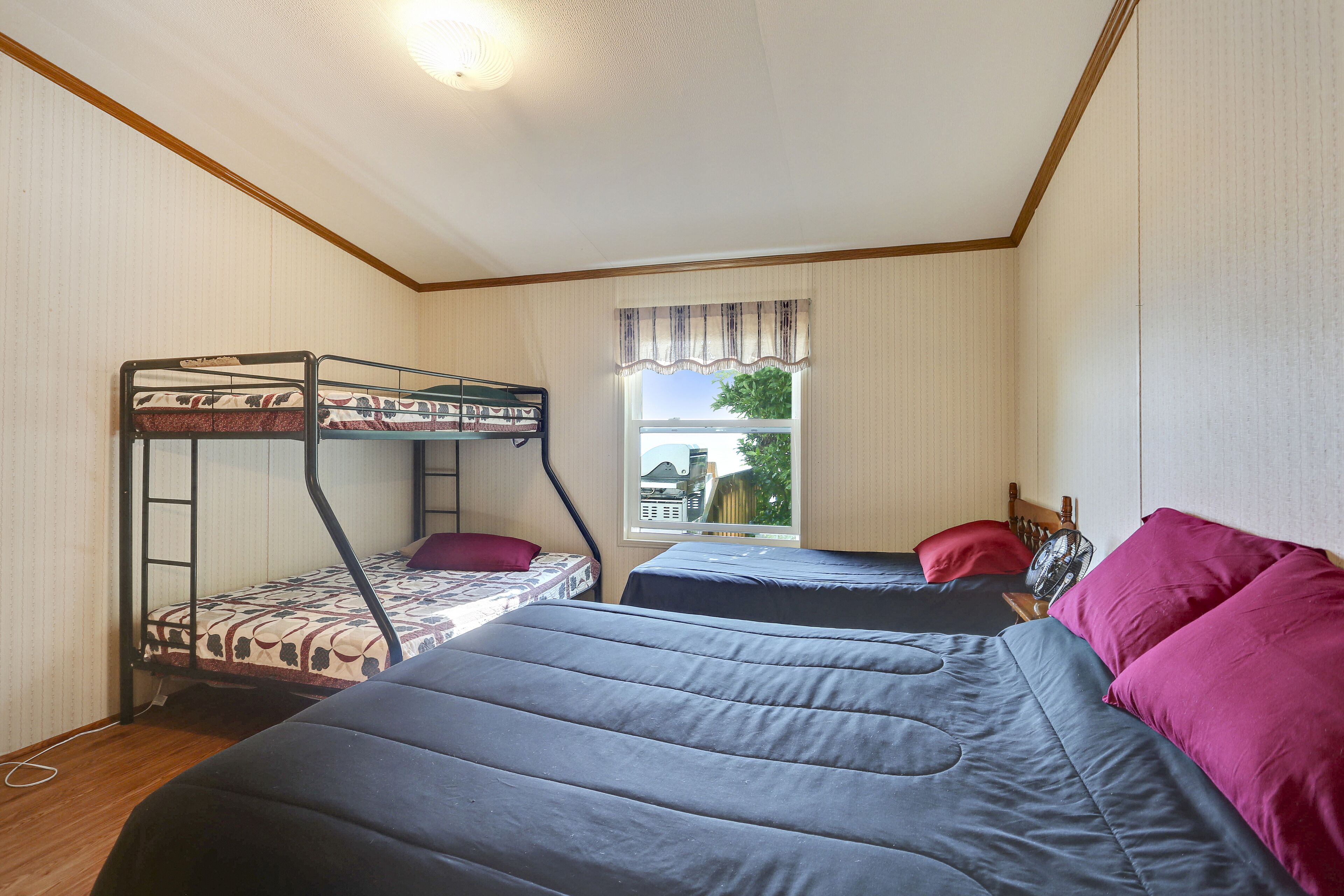 A room with bunk beds, a window with a view, and a ceiling light.