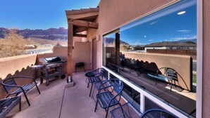 An outdoor patio with a grill, seating, and a large window offering a mountain view.