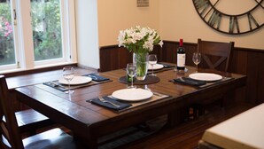 A dining table set for four with white plates, wine glasses, and a vase of flowers. - Spacious Sebastopol Home — 5-Minute Walk to Town, Wine Country at Your Doorstep (Sebastopol)