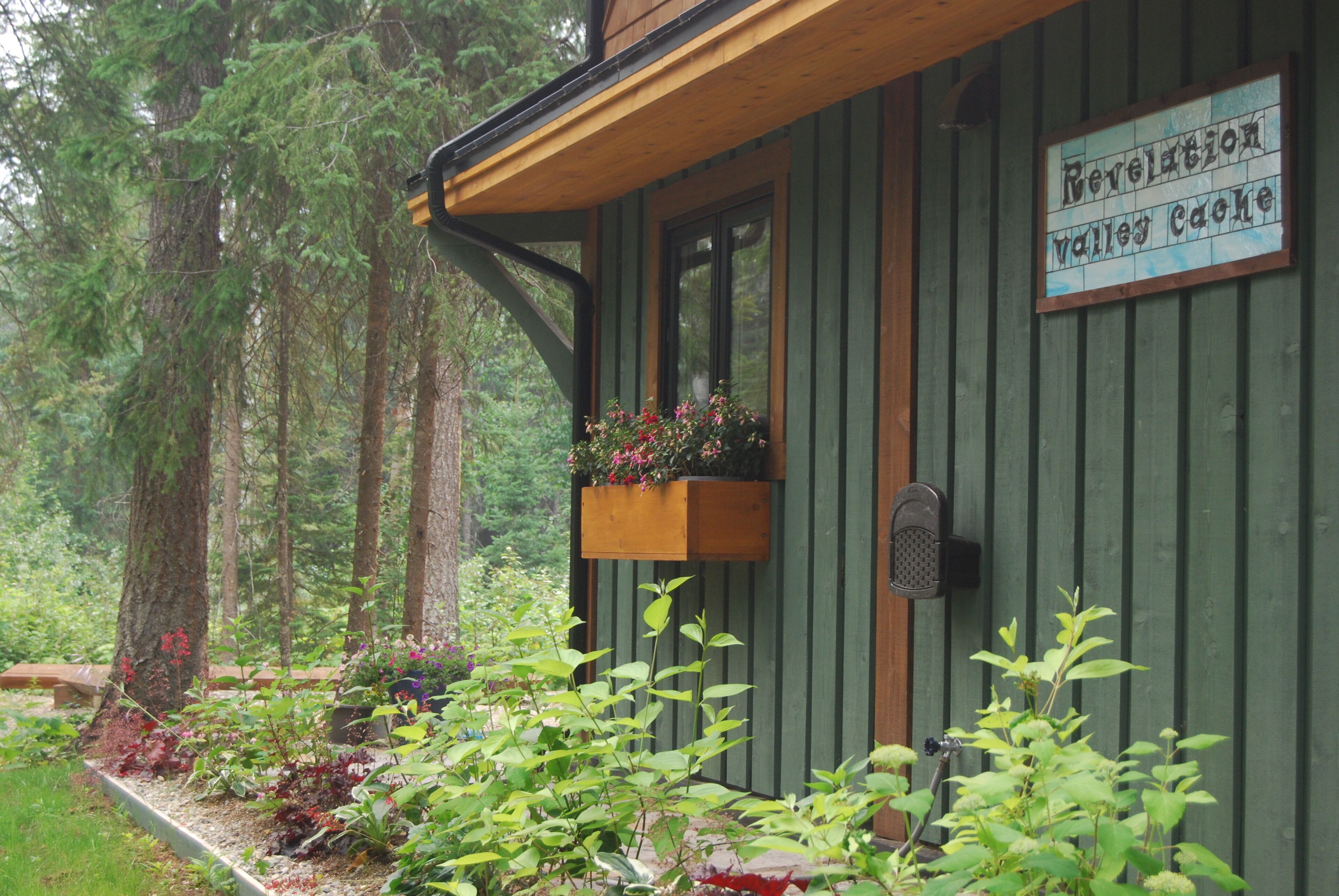 Une cabane avec une façade en bois, une fenêtre agrémentée d’une jardinière et une pancarte indiquant : « Cache de la vallée de la Révélation ».