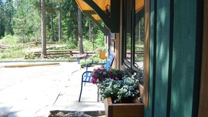 A covered outdoor seating area with wooden benches and flower planters. - Revelation Valley Carriage House near Jasper National Park (Valemount)