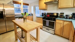 A modern kitchen with wooden cabinets, stainless steel appliances, and a wooden table.