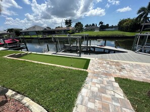 A residential area with a dock, a swimming pool, and a well-maintained lawn. - Spacious HeatedPool/Gulf Access/South Exp/Wifi/Wow! Captains Walk&Putting Green (Cape Coral)