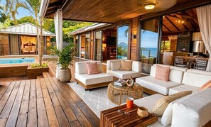 A modern outdoor living area with wooden flooring, white sofas, and a pool. - Villa Pierre: A Luxury Hidden Gem in Saint Lucia (Vieux Fort)