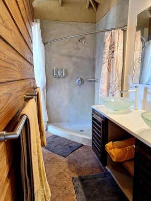 Ein Badezimmer mit Dusche, Waschbecken und Spiegel.