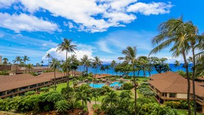 Un resort con piscina rodeada de palmeras y vistas al océano.