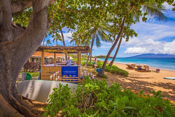 Relax in a shaded seating area overlooking the ocean, surrounded by sun loungers and umbrellas.