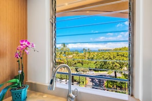 Bathroom with a serene view of lush greenery through large windows.