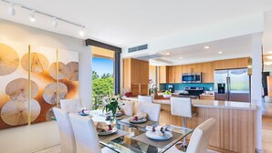 Una cocina moderna con armarios de madera, electrodomésticos de acero inoxidable y una mesa de comedor de vidrio para cuatro comensales.