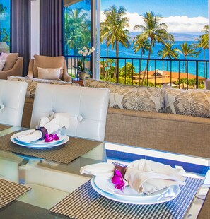 Relax in a spacious room with a sofa, armchairs, and a dining table overlooking the tropical beach.