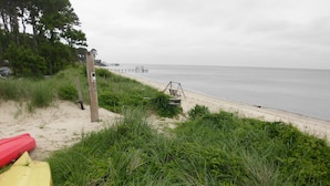 Ein Strand mit einer hölzernen Steg, der ins Meer führt, umgeben von dichtem Grün und einem sandigen Ufer.