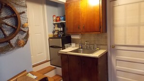 Eine kleine Küche mit Holzausstattung, einem Edelstahl-Spülbecken und einem kleinen Kühlschrank.