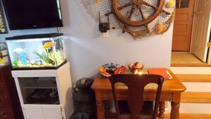 Ein Zimmer mit Fernseher, einem Aquarium, einem Holzstuhl und einem Tisch mit Snacks.