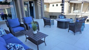 En terrasse med fletningsmøbler, et rundt bord og en potteplante.