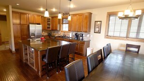 A spacious kitchen with wooden cabinets, a large island with bar stools, and a dining table with chairs.