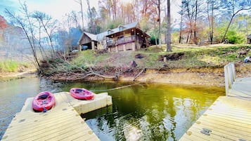 A wooden dock with kayaks and a house in the background.