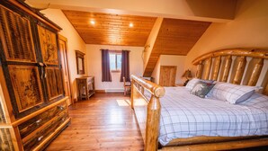 Un dormitorio de madera con una cama, cómoda y ventana con cortinas.