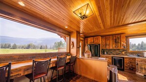 Una cocina con armarios de madera, una barra con taburetes y vistas a la montaña.
