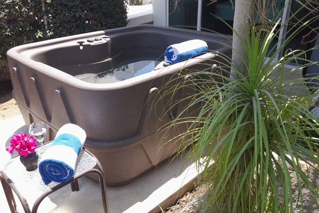 A hot tub with a blue towel and a glass of water on a table beside it.