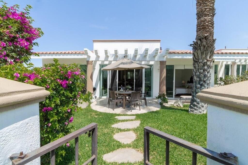 A patio with a table and chairs, a pergola, and a palm tree.