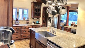 A kitchen with wooden cabinets, a stainless steel sink, and a large window. - Historic Luxury Estate - Heated Pool, Hot Tub, Fire Pit & Pool Table for 13 (Fredericksburg)