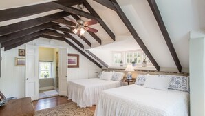 Une chambre avec deux lits, un plafond en bois et une fenêtre.